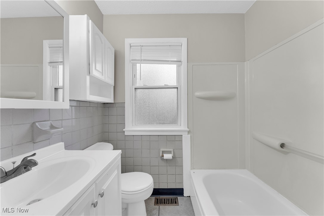 29034 Barjode Road Willowick, OH 44095 - Photo 13 of 24 Bathroom with vanity, tile walls, light tile patterned flooring, and shower / bathtub combination