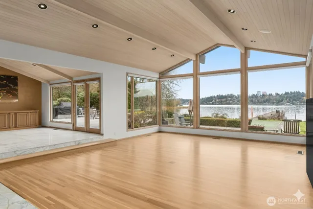 a view of an empty room with a large window and wooden floor