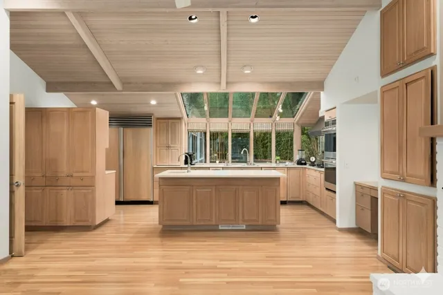 a large white kitchen with granite countertop wooden cabinets and a large window