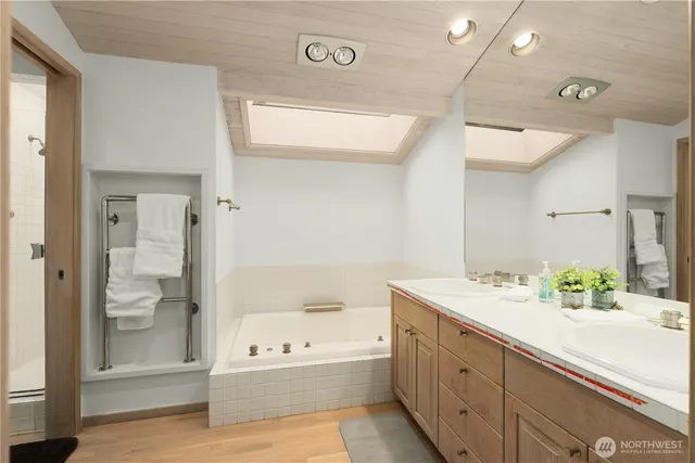 a bathroom with a tub a sink and a large mirror