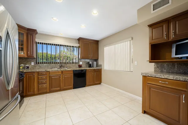 a kitchen with stainless steel appliances granite countertop a stove top oven a sink dishwasher a refrigerator and cabinets with wooden floor