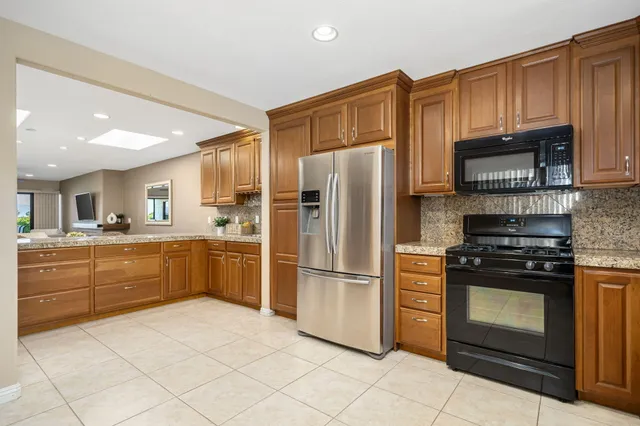 a kitchen with granite countertop a refrigerator stove top oven and sink