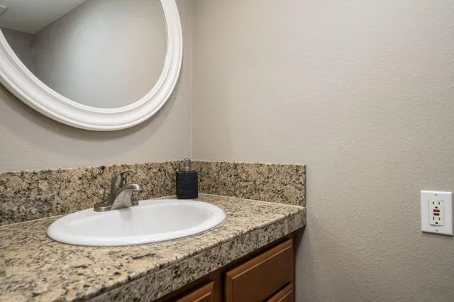 a bathroom with a granite countertop sink and a mirror