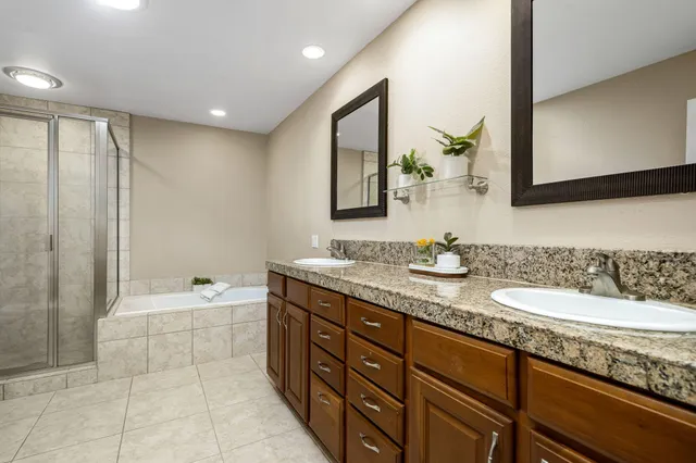 a spacious bathroom with a granite countertop sink mirror and bathtub
