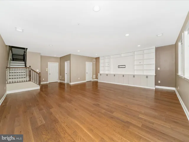 a view of an empty room with wooden floor and windows