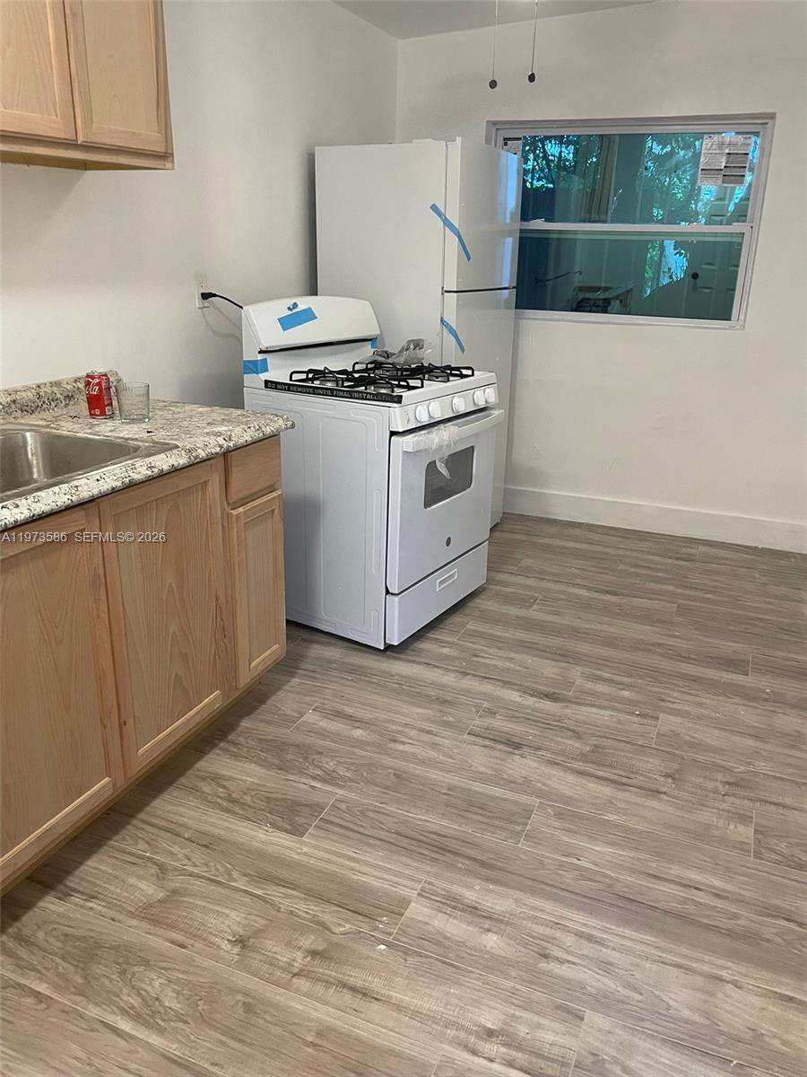 a kitchen with a stove and wooden floor