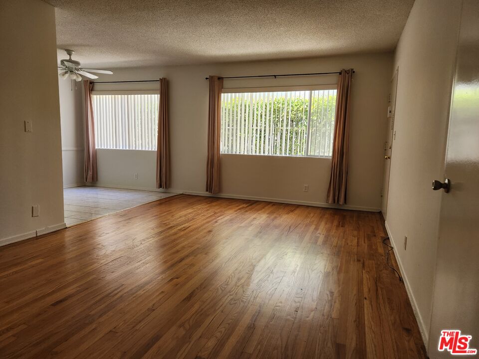 an empty room with wooden floor and windows