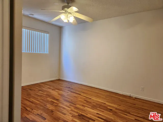 an empty room with wooden floor chandelier fan and windows