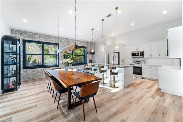 a kitchen with stainless steel appliances kitchen island granite countertop a table chairs and a wooden floor