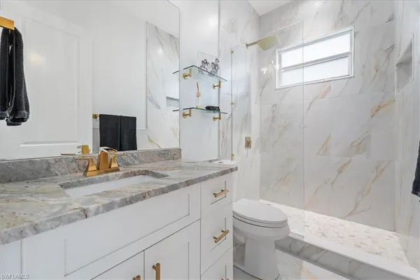 a bathroom with a granite countertop sink toilet and shower