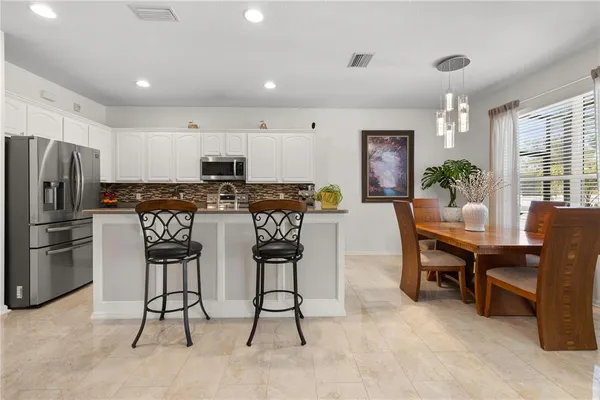 a kitchen with stainless steel appliances kitchen island granite countertop a table and chairs in it