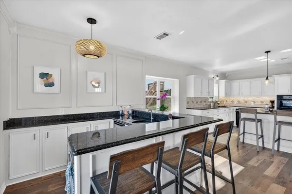 a kitchen with stainless steel appliances kitchen island granite countertop a sink and chairs