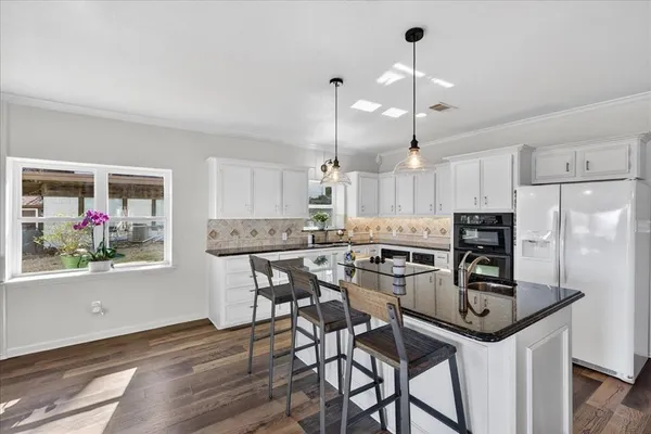 a kitchen with kitchen island a dining table chairs stainless steel appliances and cabinets