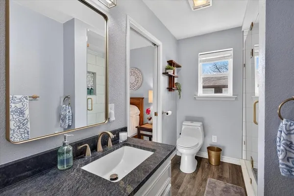 a bathroom with a granite countertop sink mirror vanity and toilet