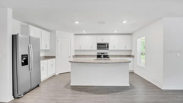 a kitchen with stainless steel appliances a refrigerator and white cabinets