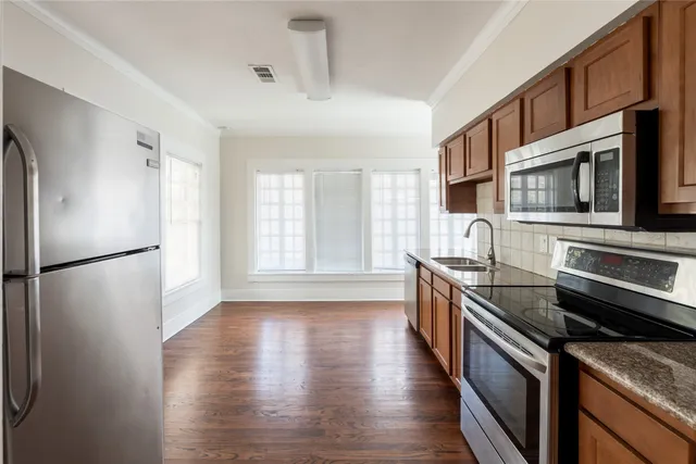 a kitchen with stainless steel appliances granite countertop a refrigerator a stove top oven a sink dishwasher and wooden cabinets with wooden floor