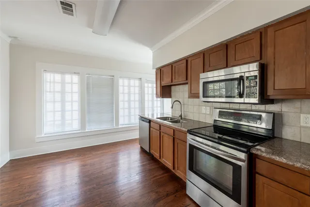 a kitchen with granite countertop wooden cabinets stainless steel appliances and a window