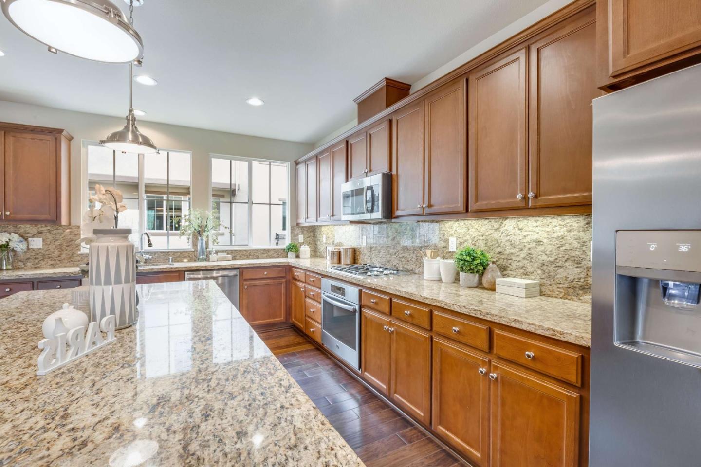 579 Holthouse Terrace Sunnyvale, CA 94087 - Photo 12 of 37 a large kitchen with granite countertop a refrigerator a sink a stove a dining table and chairs with wooden floor