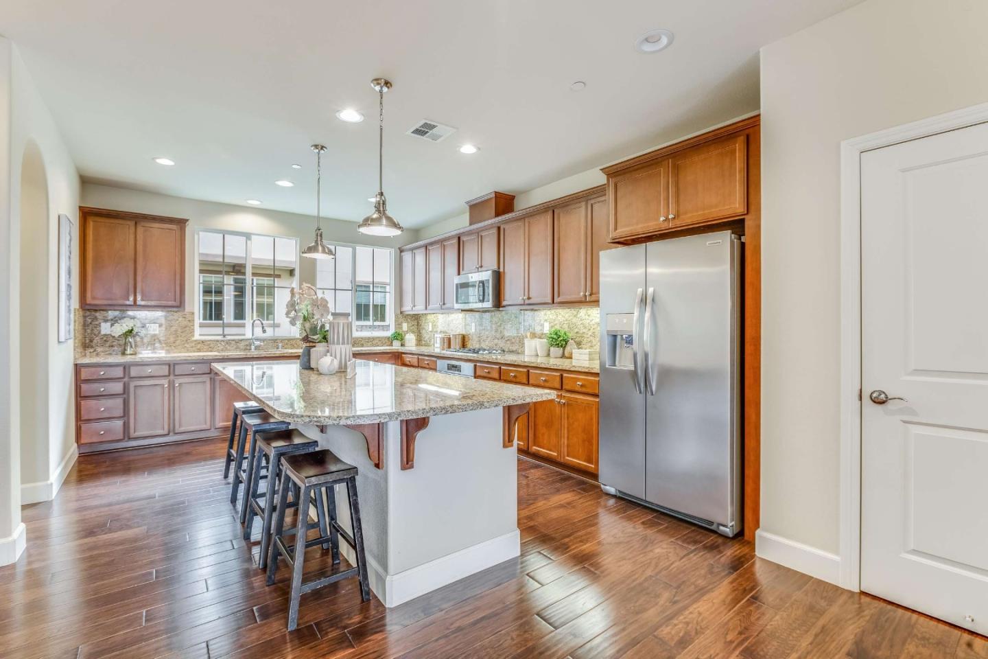 579 Holthouse Terrace Sunnyvale, CA 94087 - Photo 13 of 37 a kitchen with stainless steel appliances granite countertop a refrigerator a stove top oven a sink dishwasher and white cabinets with wooden floor