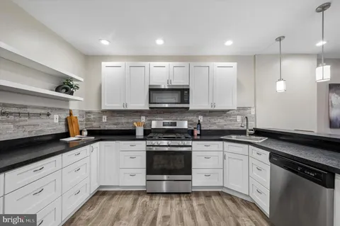 a kitchen with granite countertop white cabinets white stainless steel appliances and sink