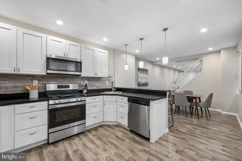 a kitchen with stainless steel appliances granite countertop a stove and a wooden floors