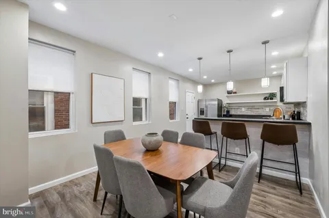 a kitchen with a dining table chairs and wooden floor