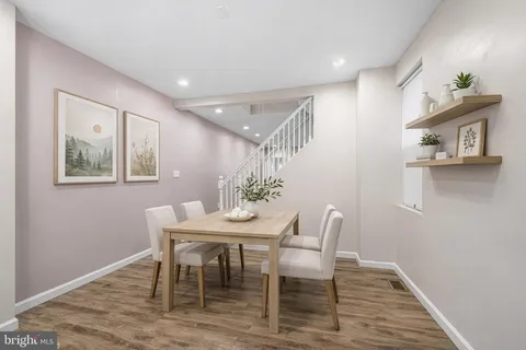a kitchen with stainless steel appliances granite countertop a table chairs in it and wooden floors