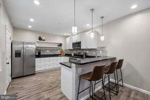 a kitchen with stainless steel appliances granite countertop a sink a stove a refrigerator and island with wooden floor