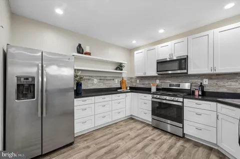 a kitchen with stainless steel appliances granite countertop a refrigerator a stove top oven a sink and dishwasher with wooden floor