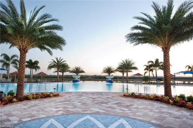 a view of swimming pool with a lounge chair and palm trees