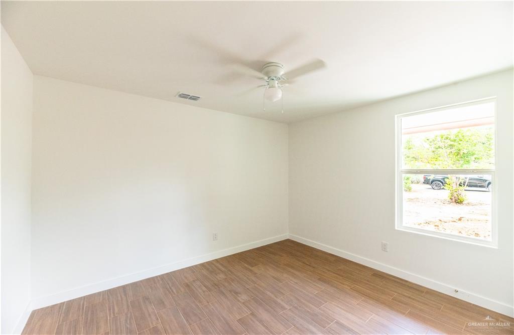 214 South 28th Street McAllen, TX 78501 - Photo 6 of 11 an empty room with wooden floor and windows