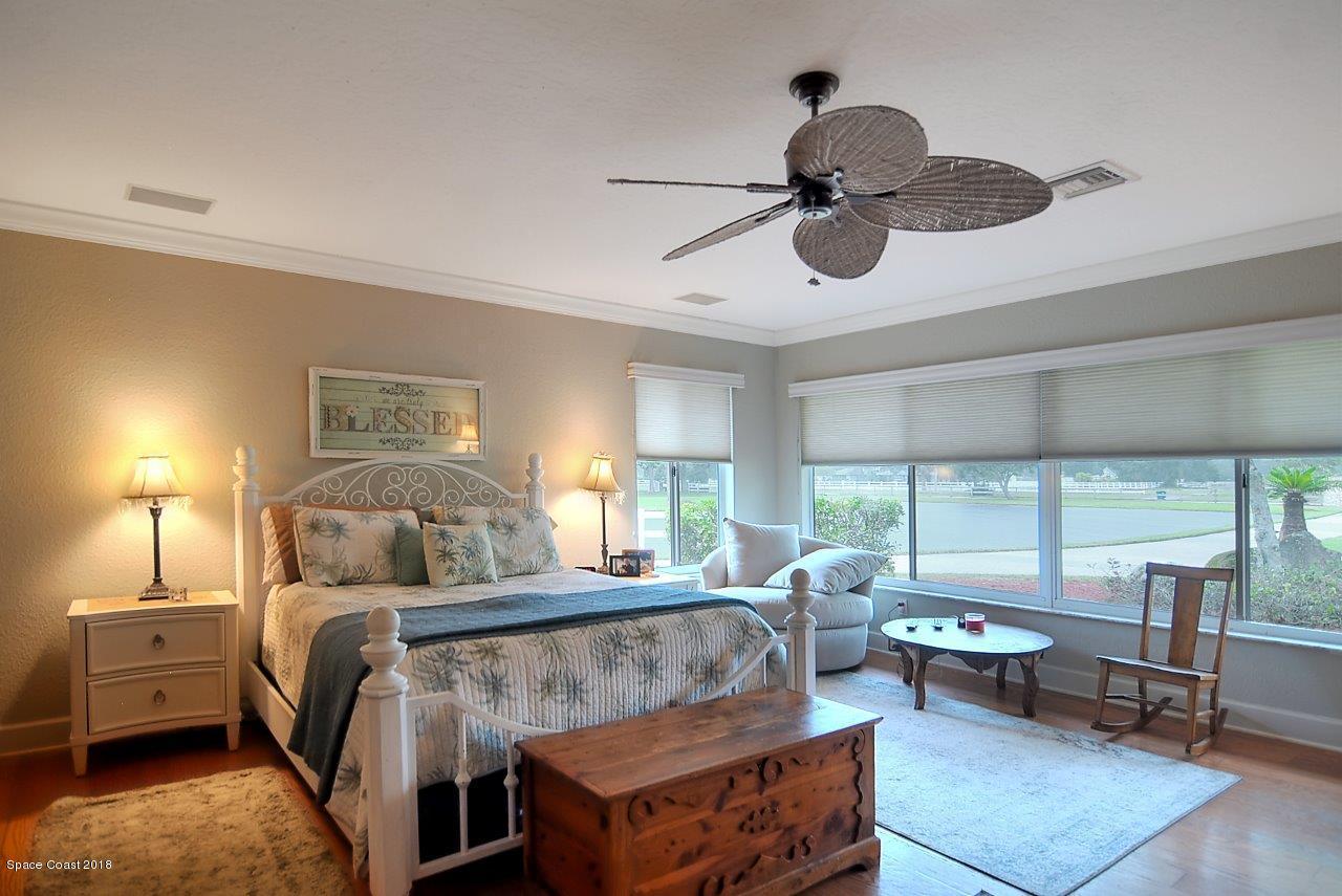 4107 Pinewood Road Melbourne, FL 32934 - Photo 15 of 32 a bedroom with a bed a large window closet and chandelier