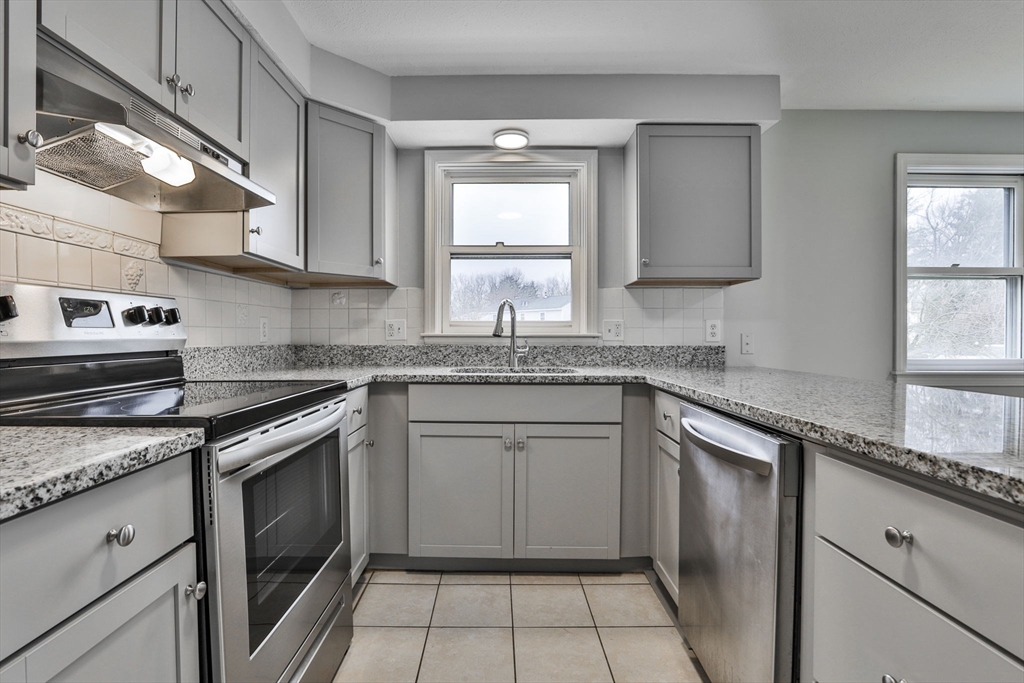 5 Norman Drive, Unit R Derry, NH 03038 - Photo 11 of 28 a kitchen with granite countertop a sink stove and cabinets