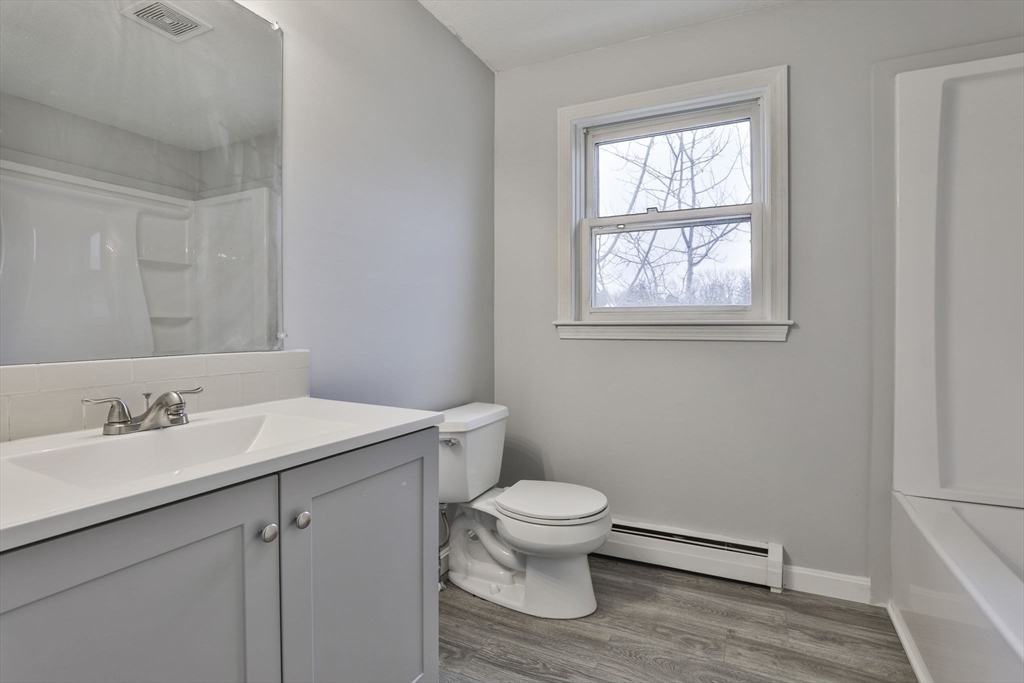 5 Norman Drive, Unit R Derry, NH 03038 - Photo 23 of 28 a bathroom with a granite countertop toilet a sink a mirror and a window