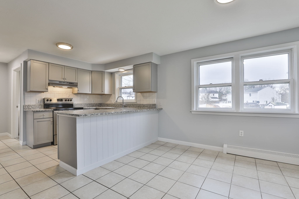 5 Norman Drive, Unit R Derry, NH 03038 - Photo 6 of 28 a kitchen with granite countertop a stove a sink and a refrigerator