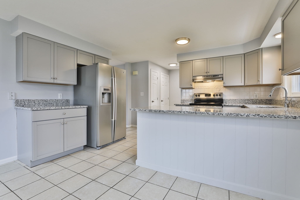 5 Norman Drive, Unit R Derry, NH 03038 - Photo 7 of 28 a kitchen with a refrigerator a stove top oven and white cabinets