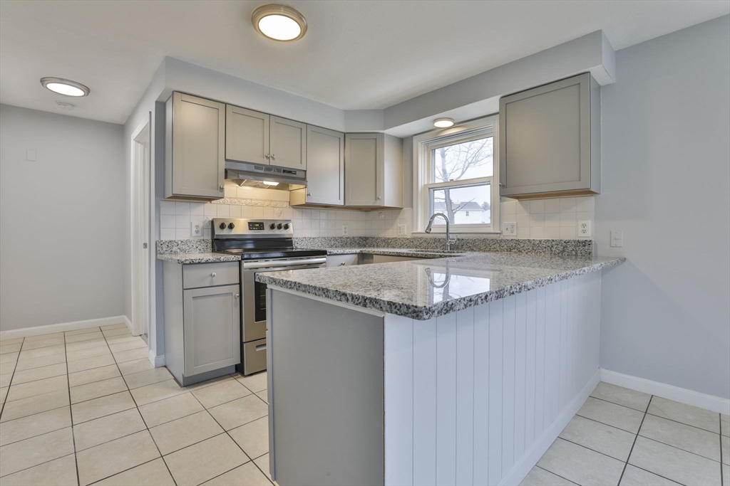5 Norman Drive, Unit R Derry, NH 03038 - Photo 8 of 28 a kitchen with stainless steel appliances granite countertop a sink stove and cabinets