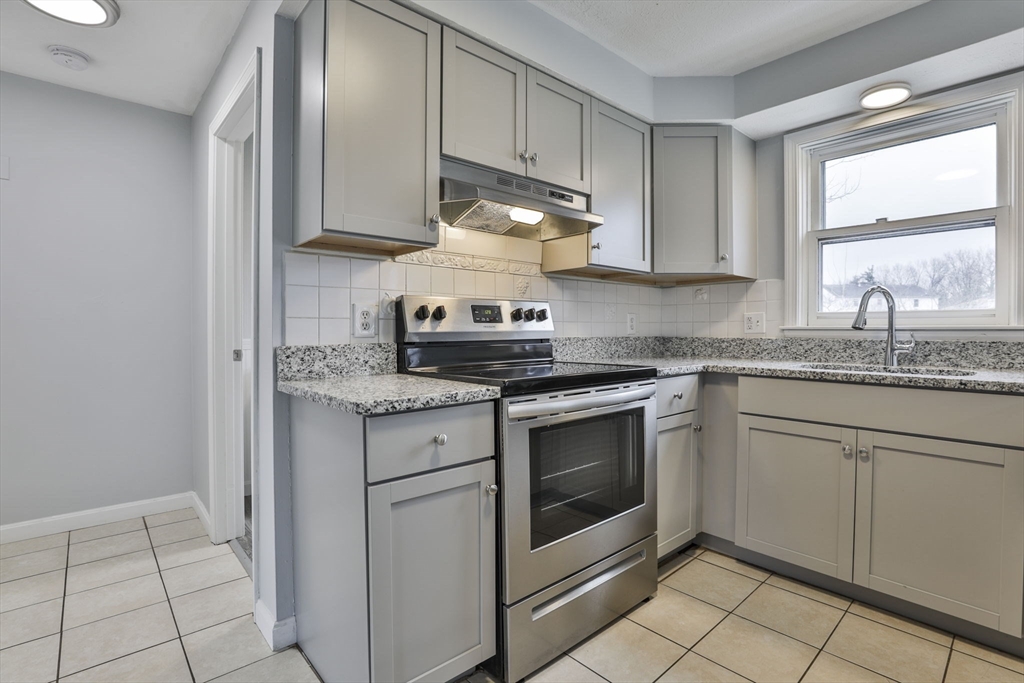 5 Norman Drive, Unit R Derry, NH 03038 - Photo 9 of 28 a kitchen with granite countertop white cabinets stainless steel appliances and a sink