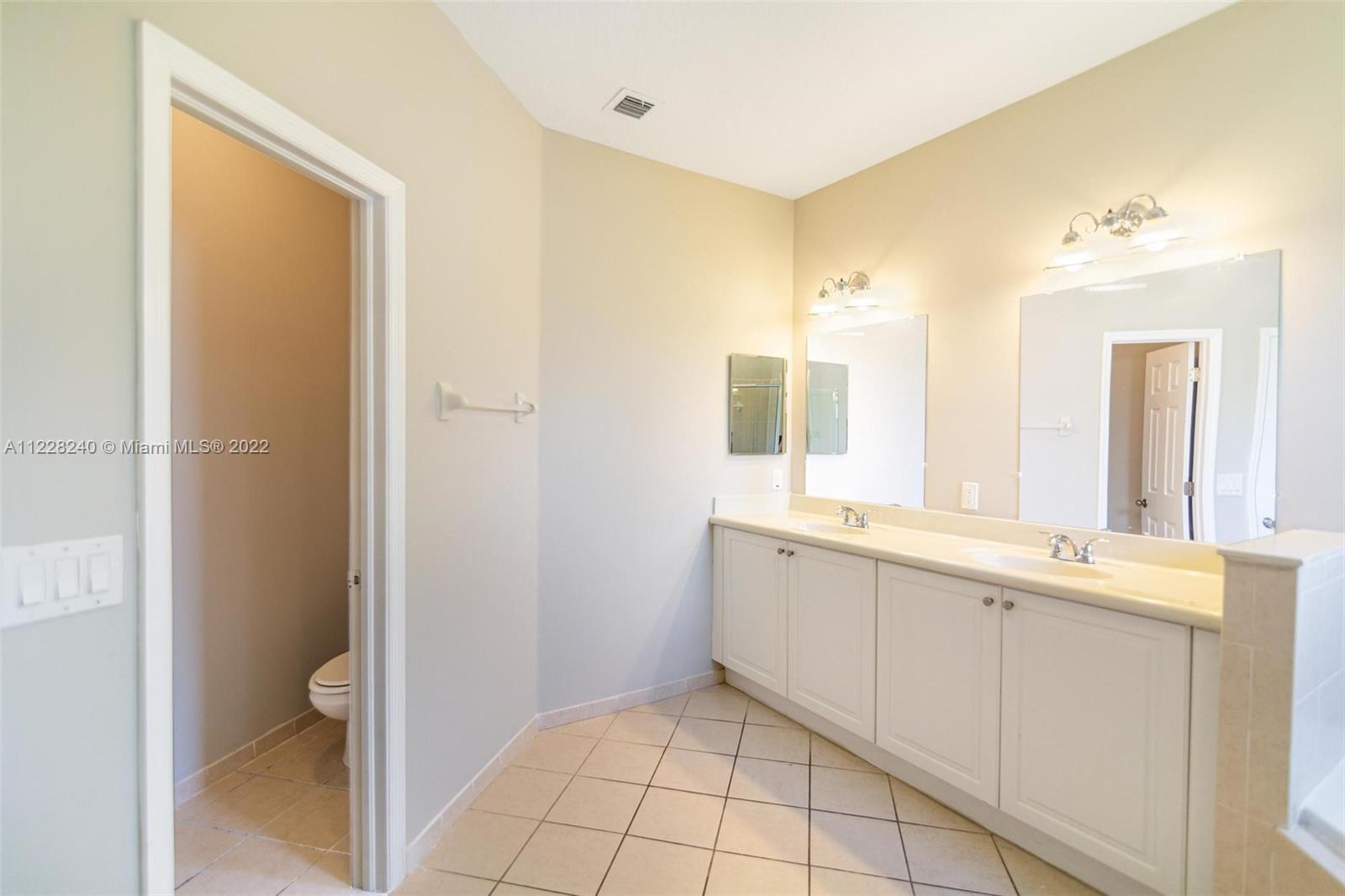 11451 Southwest 243 Terrace Homestead, FL 33032 - Photo 32 of 49 a large bathroom with a double vanity sink a toilet and a mirror