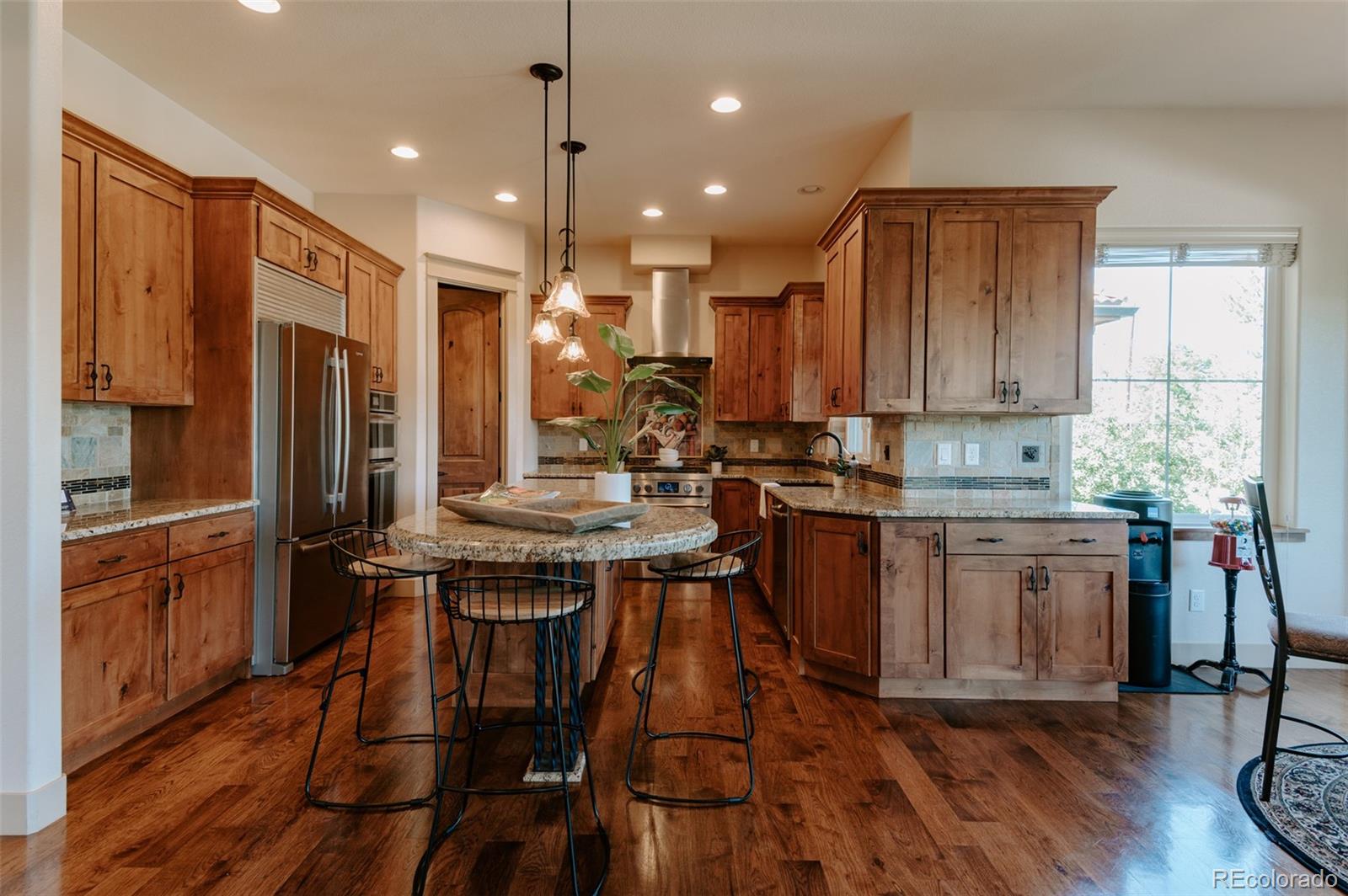 5792 Yank Street Arvada, CO 80002 - Photo 12 of 40 a kitchen with kitchen island granite countertop wooden floors and stainless steel appliances