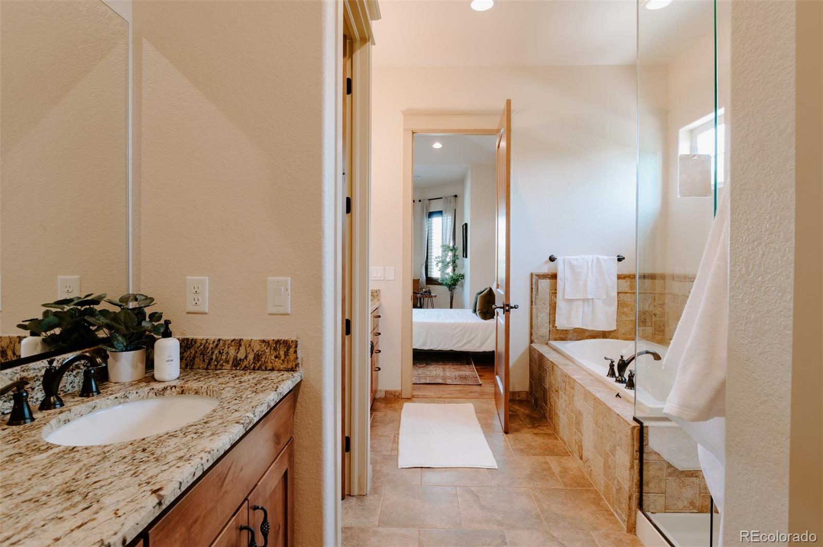 5792 Yank Street Arvada, CO 80002 - Photo 16 of 40 a en suite bathroom with a granite countertop tub and a sink