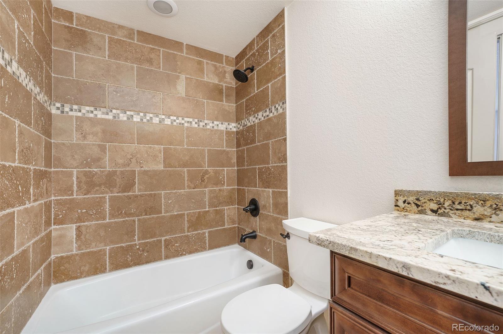 5792 Yank Street Arvada, CO 80002 - Photo 36 of 40 a bathroom with a granite countertop bathtub shower sink vanity and toilet