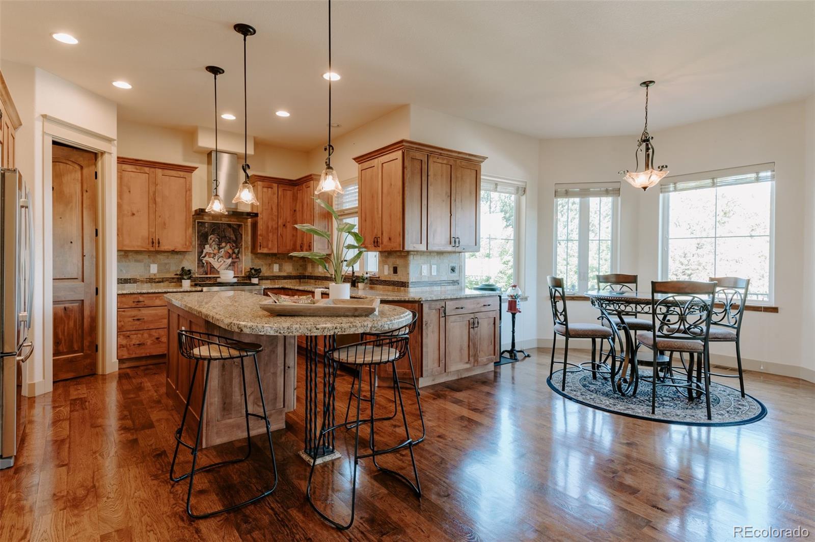 5792 Yank Street Arvada, CO 80002 - Photo 8 of 40 a kitchen with stainless steel appliances granite countertop a table chairs stove and kitchen view