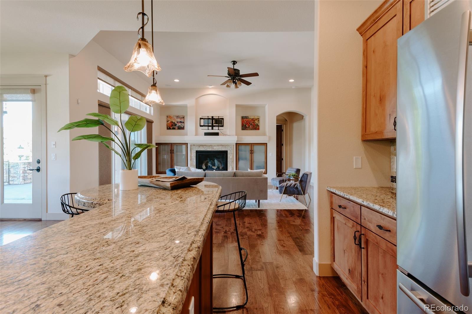 5792 Yank Street Arvada, CO 80002 - Photo 9 of 40 a open kitchen with stainless steel appliances granite countertop a stove refrigerator and a fireplace with wooden floor