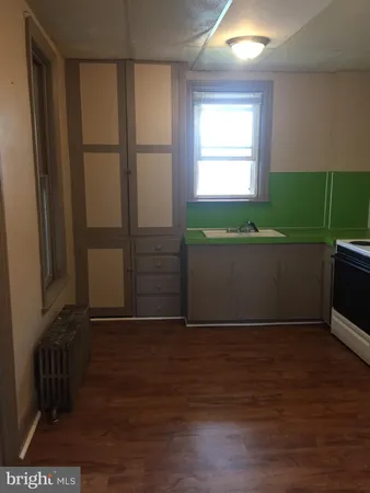 a view of a refrigerator in kitchen and an empty room