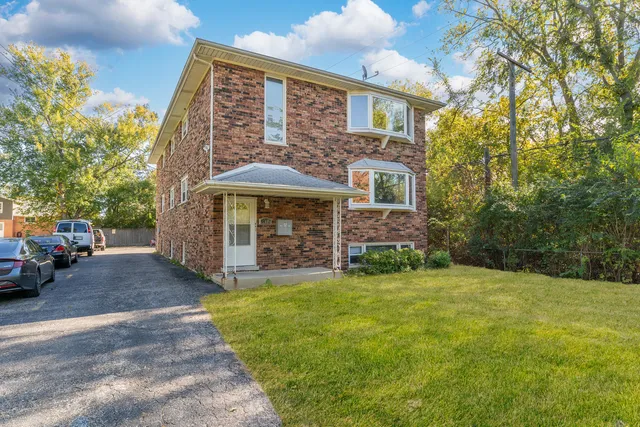 a view of a brick house with a big yard and large trees