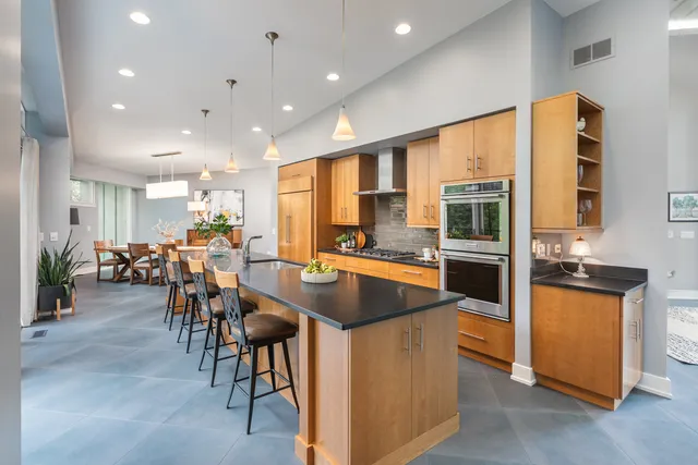 a living room with stainless steel appliances kitchen island a large window in it