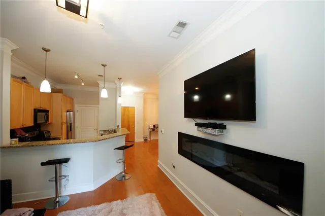 a living room with stainless steel appliances kitchen island furniture and a flat screen tv