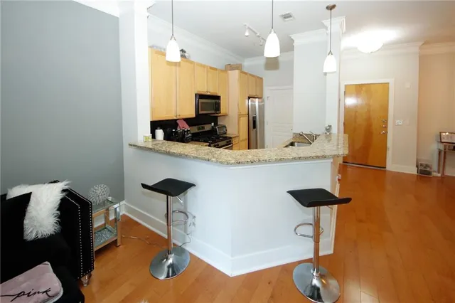 a kitchen with stainless steel appliances kitchen island a table chairs in it and wooden floors