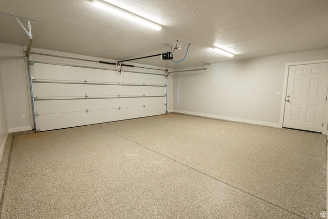 910 East Remington Road Cedar City, UT 84721 - Photo 26 of 29 Spacious garage featuring a durable epoxy floor coating, white overhead door, interior access door, and overhead lighting